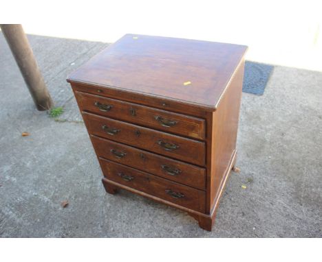 A bachelor's Georgian walnut and banded box and ebony strung chest of four long graduated drawers with brass bail handles, on