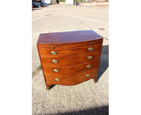 A bachelor's Georgian mahogany box line inlaid bowfront chest of four long graduated drawers with oval handle plates, on spla