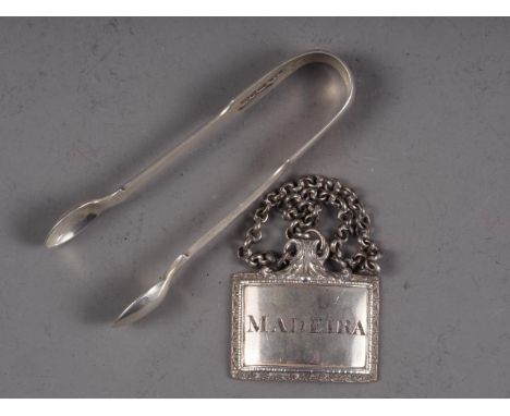 A silver plated Madeira decanter label and a pair of silver sugar tongs 
