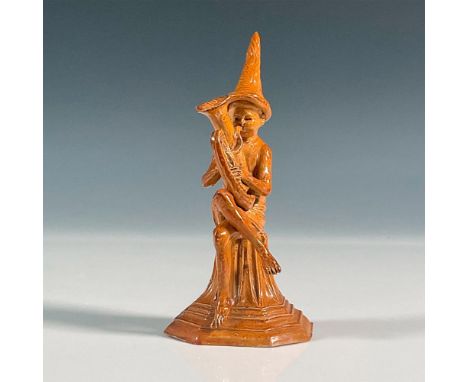 Stoneware figure of the Merry Musician series. Modeled as a boy seated on a tapering plinth playing a musical instrument. Inc