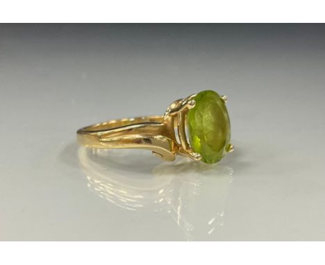 A Princess Cruises Peridot twist ring, oval peridot quarter claw set within 14 ct gold shank, stamped 14k, size N, 4.6g gross