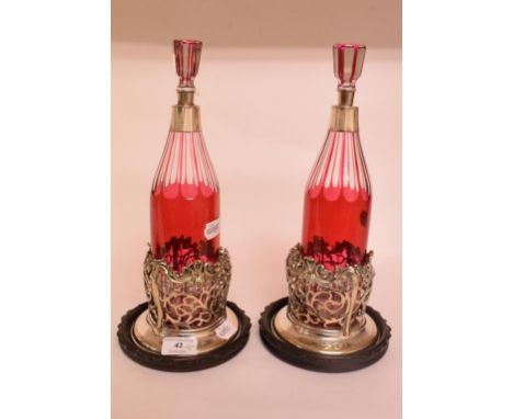 A pair of clear and cranberry flashed glass decanters and stoppers, with silver plated mounts, 31 cm high, with a pair of pla