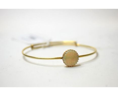 A yellow coloured metal bangle, applied an opal cabochon   Condition report  Approx. 9.7 g (all in) roundall is approx. 12 mm