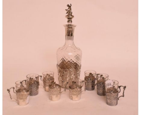 A silver mounted glass liqueur decanter, with rococo style decoration, and eight similar silver liqueur cups, with some glass
