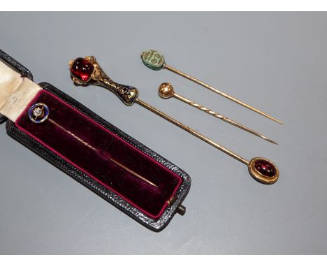 An Edwardian diamond and blue enamel set stick pin and three other stick pins including scarab and cabochon set enamelled cla