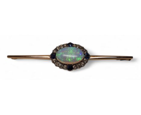 A rose gold coloured metal bar brooch, the central setting set with a oval black opal 12 x 19mm, bordered by sixteen round ol