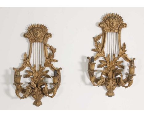 A pair of carved wooden wall lights,early 20th century, in the 18th century taste, each painted gold, of lyre shape, with two