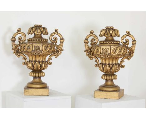 A pair of carved and painted softwood urns,mid-19th century, Italian, each ornately carved and on a square base, drilled for 