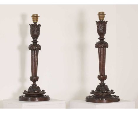 A pair of Edwardian carved mahogany table lamps,each with a turned, tapering and fluted column with carved foliage on a turne