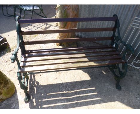 A SLATTED GARDEN BENCH, with cast iron ends incorporating serpentine and floral detail