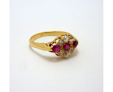 A VICTORIAN 18CT GOLD RUBY AND DIAMOND RING, with three circular rubies, flanked by a surround of old cut diamonds, estimated