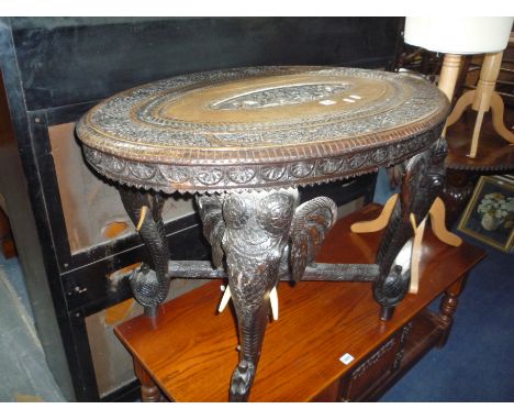 A HEAVILY CARVED OVAL OCCASIONAL TABLE, supported on elephant trunk supports