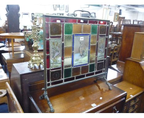 A BRASS FRAMED FIRESCREEN, with lead glazed inset panel containing various decorated and coloured glass panels, including Her