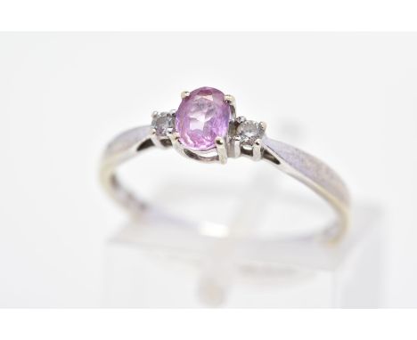 A GEM SET RING, designed as a central oval pink gem, assessed as topaz, flanked by brilliant cut diamonds, estimated total di