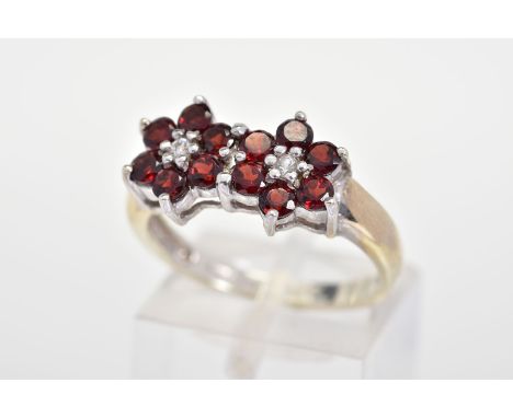 A 9CT GOLD GARNET AND DIAMOND RING, designed as two flowers each with six circular cut garnets with a central brilliant cut d