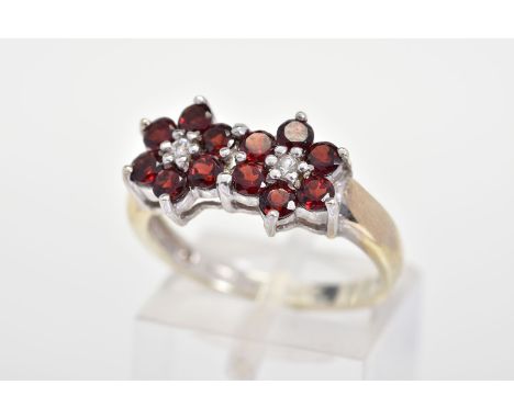 A 9CT GOLD GARNET AND DIAMOND RING, designed as two flowers each with six circular cut garnets with a central brilliant cut d