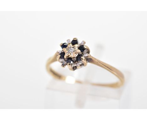 A 9CT GOLD SAPPHIRE AND DIAMOND RING, of tiered design with a central single cut diamond and circular cut sapphire surround, 