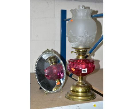 A BRASS TWIN BURNER OIL LAMP, having cranberry glass reservoir and satin finish milk glass shade with pressed fleur de lys de