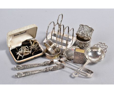 A SELECTION OF SILVERWARE, to include a Mappin &amp; Webb toast rack, two pairs of napkin rings, a bottle label, a nut cracke