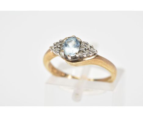 A 9CT GOLD AQUAMARINE AND DIAMOND RING, the central oval aquamarine flanked by a triangle cluster of six single cut diamonds 