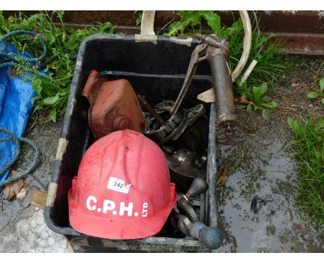 A tub of motor parts, grease gun, hand drill and safety helmet