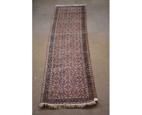 A Caucasian hand woven wool runner, worked with an all over floral design against a red ground, 355 x 84cm.