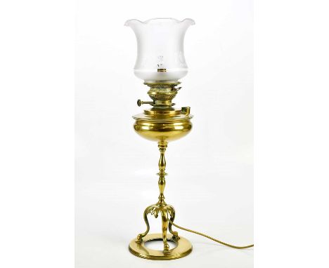 An early 20th century brass oil lamp with replacement frosted glass shade, on three scrolling legs, height including shade 67