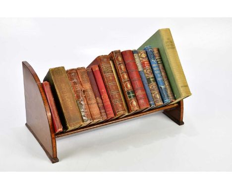 An Edwardian inlaid mahogany book trough containing a selection of decorative books, length 46cm.