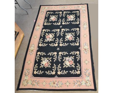 A tapestry carpet, worked with floral motifs against a black ground, 260 x 158cm.Condition Report: A little grubby and with s