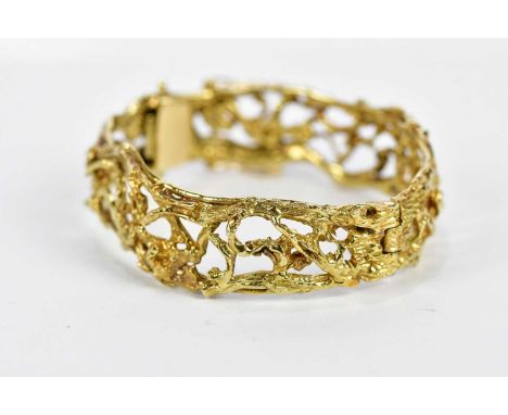 A yellow metal textured openwork hinged snap bangle of abstract pierced design, stamped '14K', internal width 57mm, approx 53