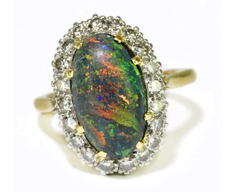 A yellow metal black opal and diamond set ring, the domed opal set within a border of twenty round brilliant cut diamonds, si