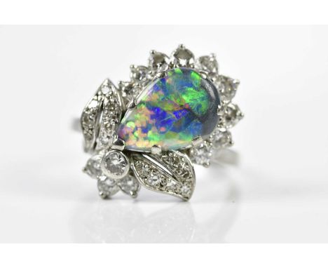 A white metal black opal and diamond cluster ring, the opal approx. 13 x 8mm, in claw setting with spray design cluster of le