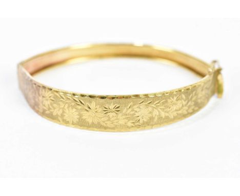 A yellow metal hinged snap bangle, with bright cut decoration, approximate weight 9.7g.