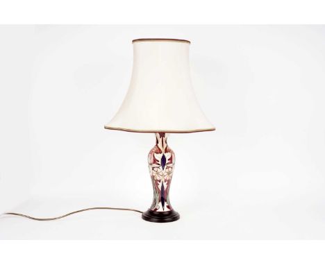 A Moorcroft Art Nouveau style table lamp, decorated with pink flowers and cream, green, and blue foliage on a dark pink backg