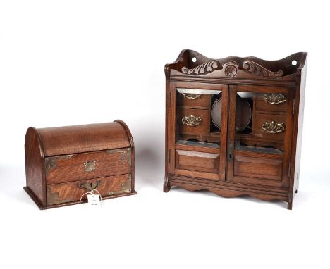 An early 20th Century walnut smoker’s cabinet, the hinged doors with glazed panel, opening to reveal brass pipe stands on the