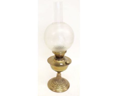 A brass oil lamp with etched glass globe shade