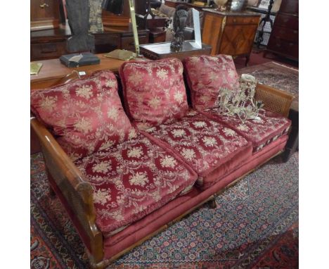 A late 19th century walnut bergere three seater sofa with floral upholstery having double caned sides and raised on scalloped