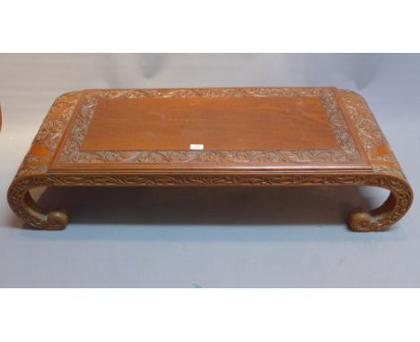 A 20th Century Chinese hardwood coffee table with floral carving and raised on scroll legs. H-30cm W-124cm D-44cm