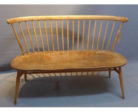 An Ercol two seater elm bench raised on tapered legs.