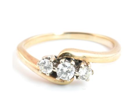 A 9ct gold and diamond three stone crossover ring. The 9ct yellow gold ring having three round brilliant cut diamonds set in 