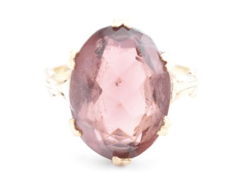 A 1970s hallmarked 9ct gold and purple stone ring. The ring set with a single oval cut purple stone to pierced, fleur-de-lis 