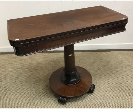 A Victorian mahogany card table, the rounded rectangular fold-over top opening to reveal a circular baize-lined interior over