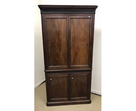 A 19th Century mahogany free standing corner cupboard, the moulded dentil cornice above a blind fretwork frieze and two panel