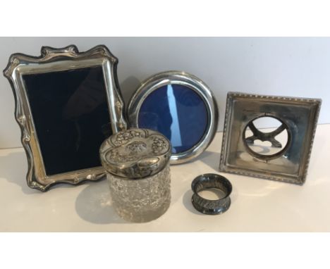 Three various silver photograph frames, a hobnail cut glass cylindrical hair tidy with silver cover and a waisted and embosse