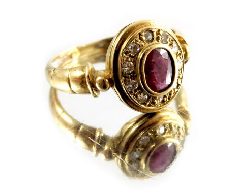 A ruby and diamond ring, set in 18 carat French gold, the central oval stone within a border of ten smaller stones, approx. J