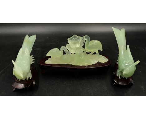 Two carved green jade exotic birds together with a carved jade group of two herons with fish and flowers. All with wooden sta