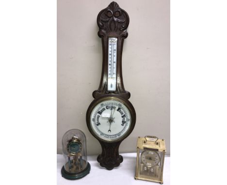 An oak aneroid barometer with thermometer. 84 h x 26cm w together with a gilt and green Kundo anniversary clock in a glass do