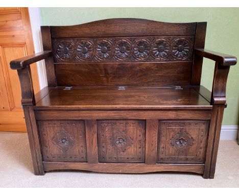 A carved oak monks bench with lift up seat. Height to back 90cm h x 106cm w  x 41cm d. 