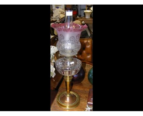 A brass oil lamp with glass reservoir and flared pink glass shadeCONDITION REPORTas per images2 small chips found to shade as