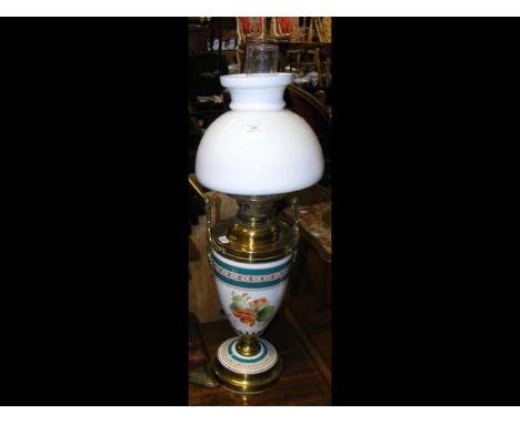 A porcelain and brass oil lamp with milk glass shade